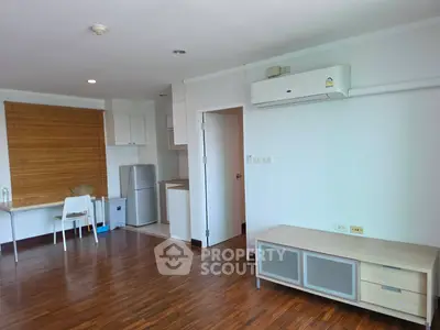 Spacious living room with wooden flooring and modern furnishings in a stylish apartment.