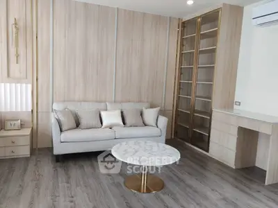 Modern living room with elegant sofa, marble coffee table, and built-in wooden shelves.