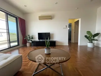 Spacious living room with parquet flooring and balcony access