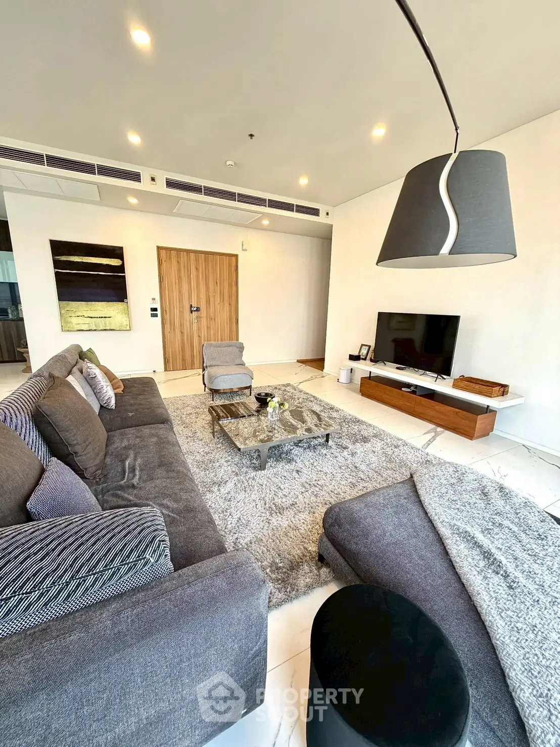 Luxurious modern living room with plush gray sofas, stylish decor, and a sleek entertainment center.