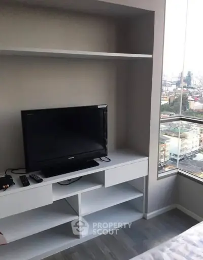 Modern bedroom with city view and sleek TV setup in urban apartment