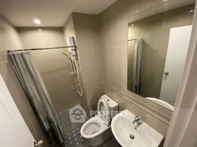 Modern bathroom with sleek fixtures and neutral tiles, featuring a shower and toilet.