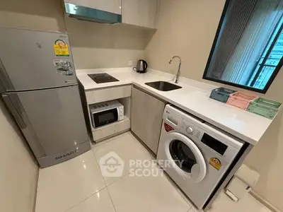 Modern compact kitchen with appliances including fridge, microwave, and washing machine.