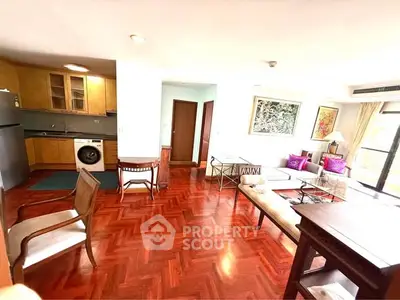 Spacious living room with wooden flooring and modern furniture in a bright apartment.