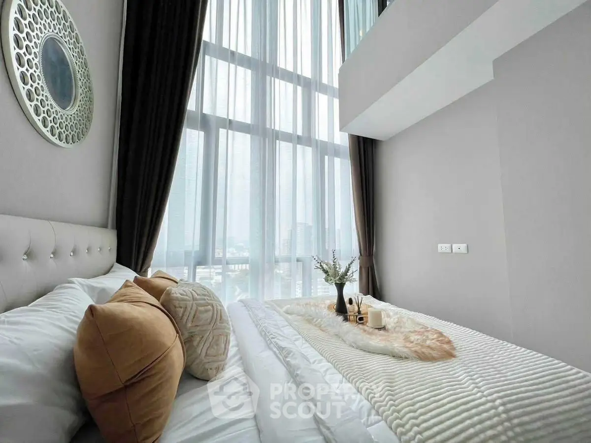 Luxurious bedroom with floor-to-ceiling windows and elegant decor in modern apartment.