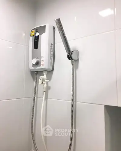 Modern bathroom with sleek white tiles and a wall-mounted shower heater.