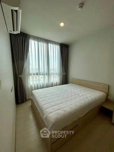 Cozy bedroom with large window and modern furnishings in a bright apartment.