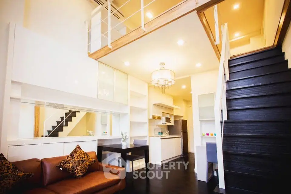 Modern loft-style living room with open kitchen and elegant staircase