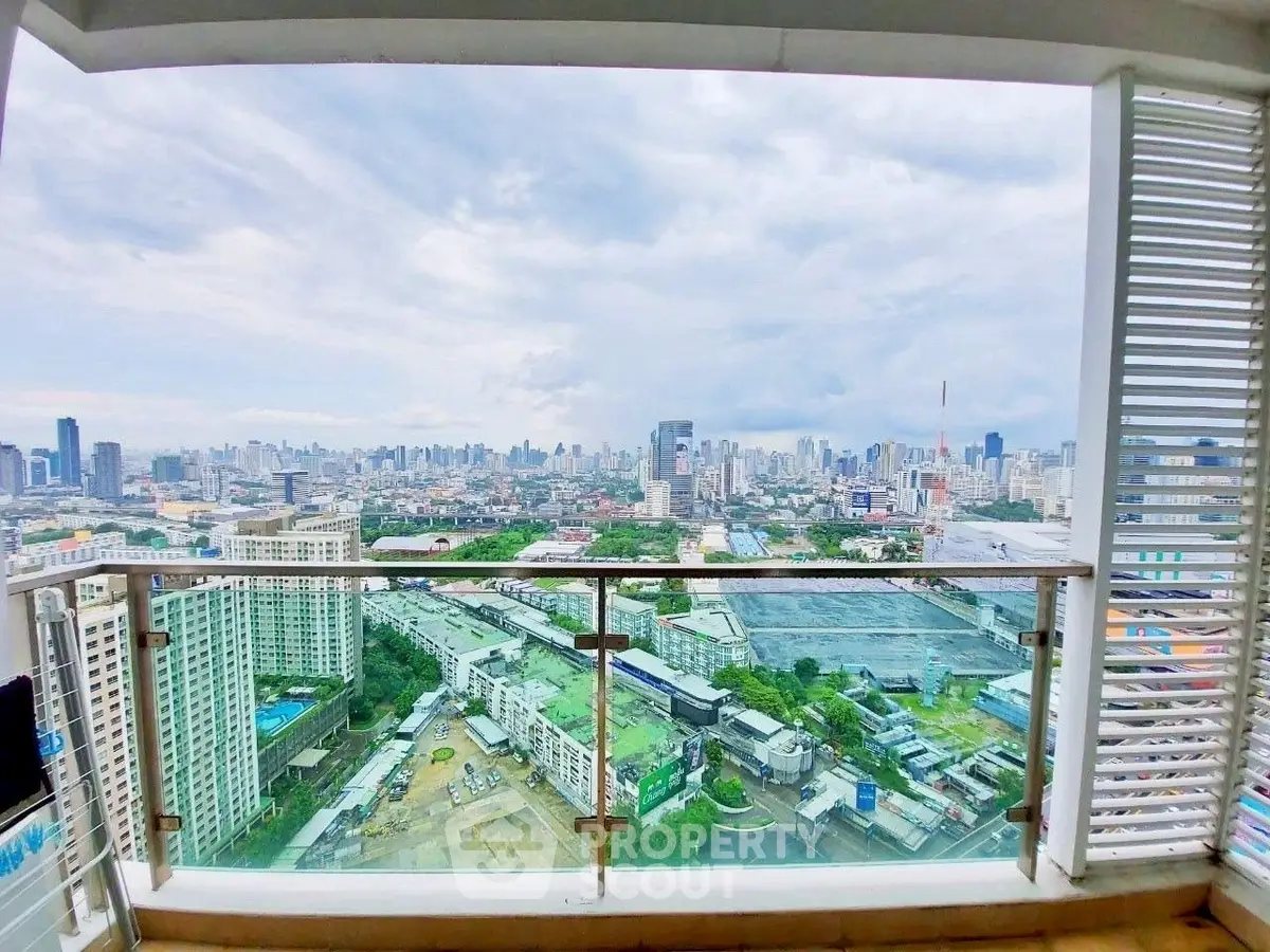 Stunning cityscape view from a high-rise balcony with glass railing, perfect for urban living.