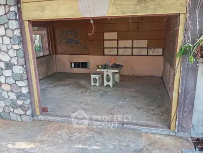 Spacious unfinished garage with stone wall exterior and open entrance, ideal for customization.