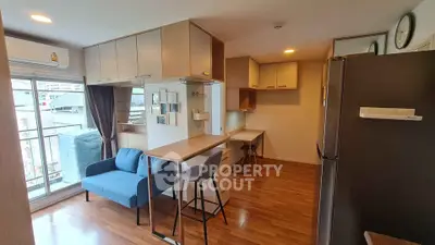 Modern apartment interior with open kitchen and cozy living area, featuring a blue sofa and balcony view.