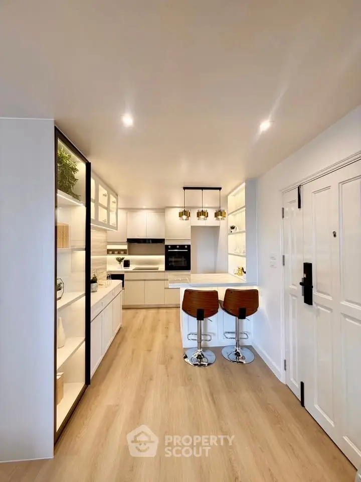 Modern kitchen with sleek design, featuring open layout and stylish bar stools, perfect for contemporary living.