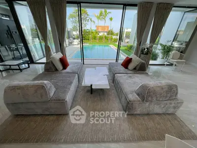 Luxurious living room with modern sofas and stunning pool view, perfect for relaxation and entertainment.