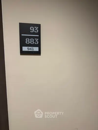 Apartment hallway with room number signage on beige wall.