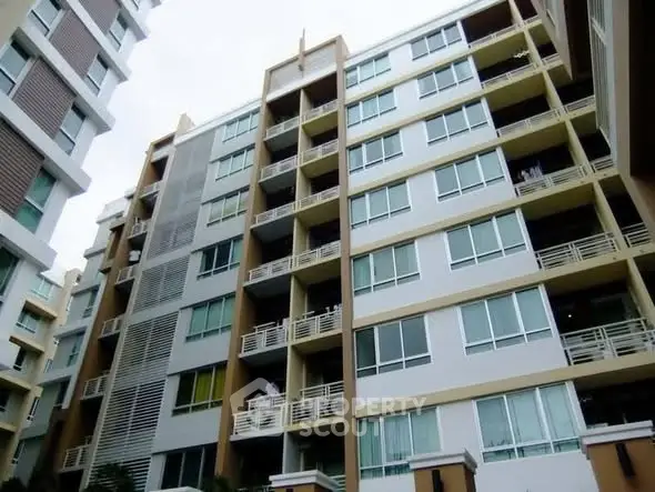 Modern multi-story apartment building with balconies and large windows.