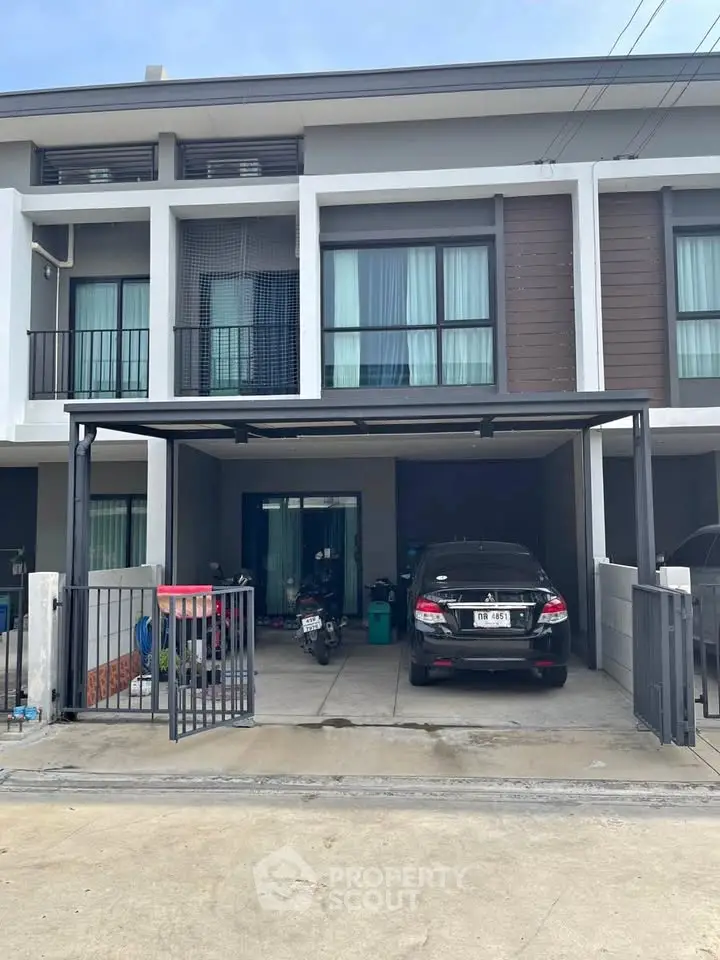 Modern townhouse with covered parking and balcony in urban setting.