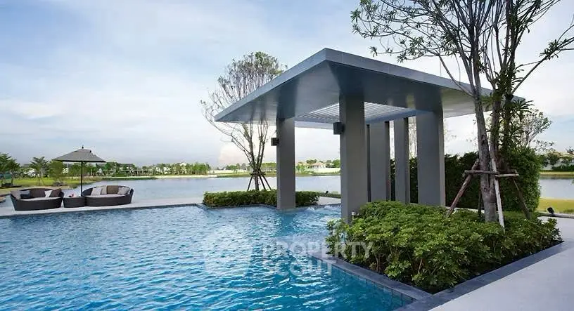 Luxurious outdoor pool with modern cabana and serene lake view, perfect for relaxation and leisure.