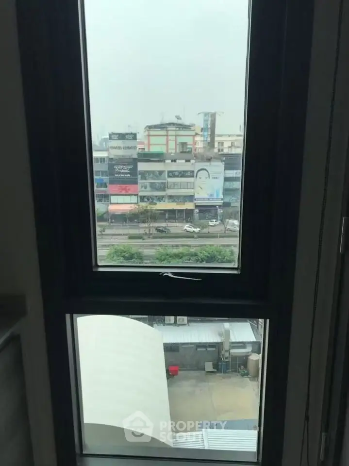 Urban view from a window showcasing city buildings and street below.