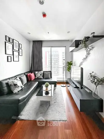 Modern living room with sleek black sofa, stylish decor, and large window offering city view.