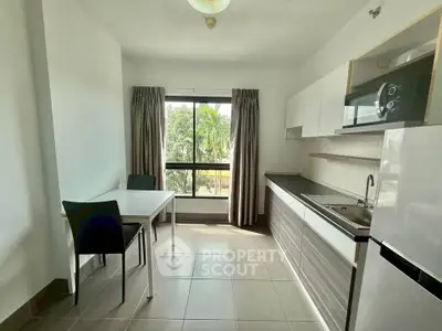 Modern kitchen with sleek cabinetry and large window offering natural light and garden view.