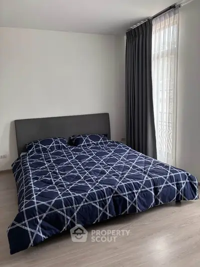Spacious bedroom with modern decor and large window for natural light.