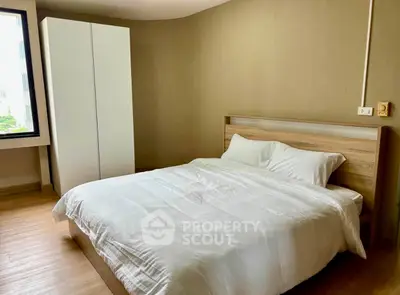 Spacious bedroom with modern wooden flooring and large window for natural light.