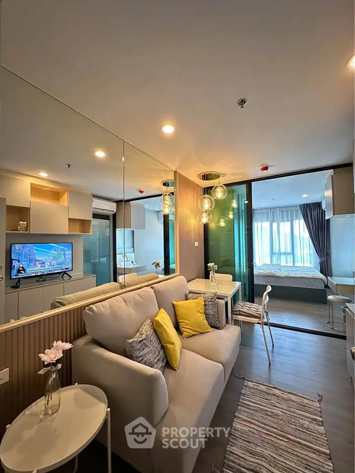 Modern living room with stylish decor and open view to bedroom, featuring cozy sofa and elegant lighting.