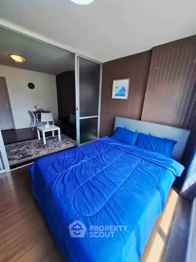 Modern bedroom with blue bedding and sliding glass doors leading to a cozy dining area.