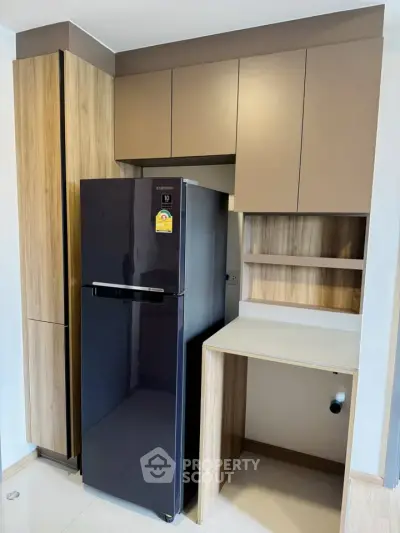 Modern kitchen with sleek cabinetry and stylish refrigerator in compact layout.