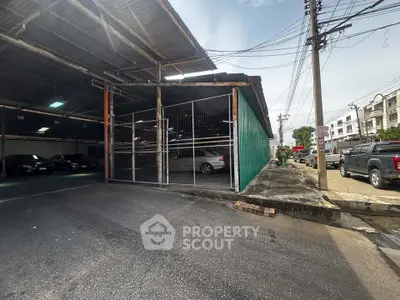 Spacious industrial warehouse with ample parking and secure fencing in a bustling commercial area.