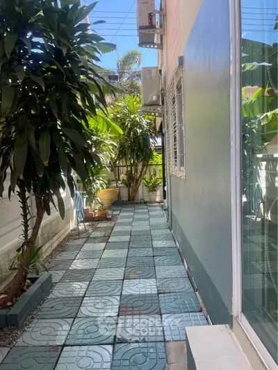 Charming outdoor walkway with lush greenery and tiled path in residential property