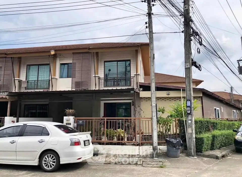 Charming two-story townhouse with balcony and lush greenery in a serene neighborhood.