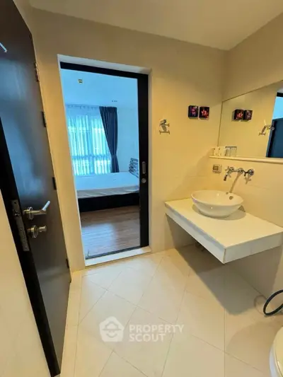 Modern bathroom with sleek fixtures and a view into a cozy bedroom
