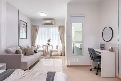 Modern studio apartment with cozy living area and workspace, featuring elegant decor and natural light.