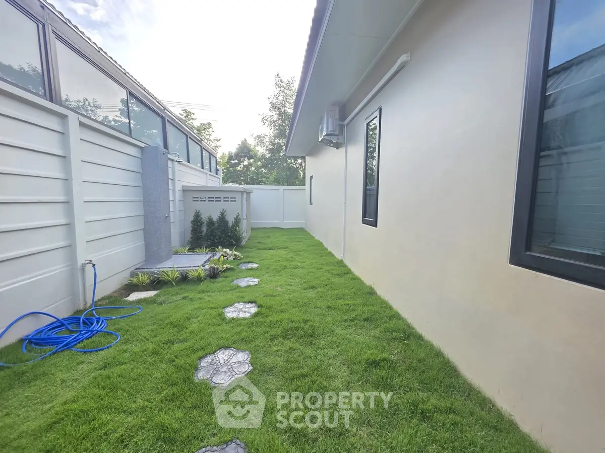Charming side garden with lush green lawn and stepping stones, perfect for outdoor relaxation and enjoyment.