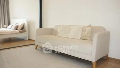 Modern living room with beige sofa and cozy bedroom view