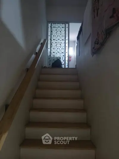 Cozy staircase leading to a private upper floor with a modern design and wooden handrail.
