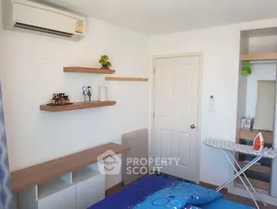 Cozy bedroom with modern decor, air conditioning, and ironing board, perfect for comfortable living.