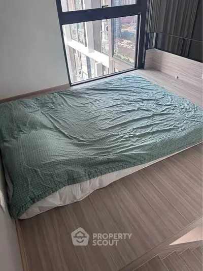 Modern bedroom with large window and city view, featuring a minimalist design and cozy bedding.