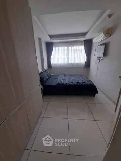 Modern bedroom with sleek design, featuring a comfortable bed, wall-mounted TV, and ample natural light.