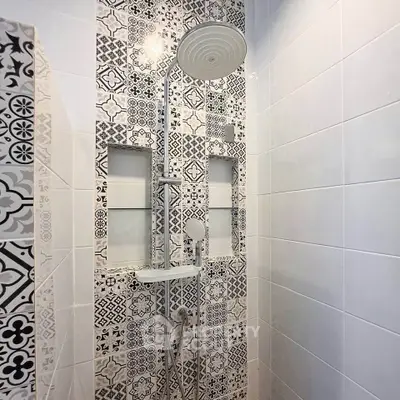 Stylish bathroom shower with intricate black and white tile design and modern fixtures.