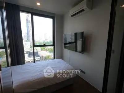 Modern bedroom with city view, featuring a wall-mounted TV and air conditioning.