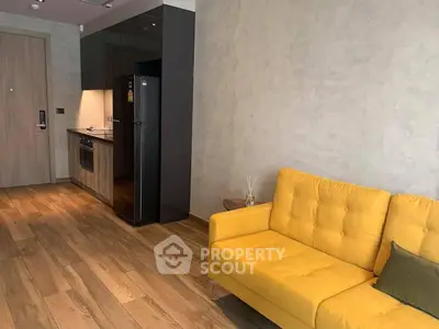 Modern living room with yellow sofa and sleek kitchen area in open layout apartment.