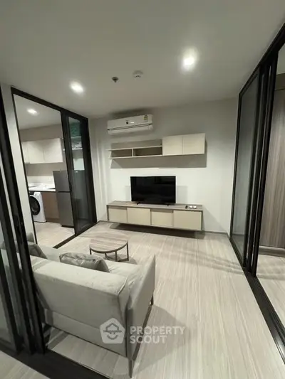 Modern living room with sleek design and open layout, featuring a cozy sofa and wall-mounted TV.
