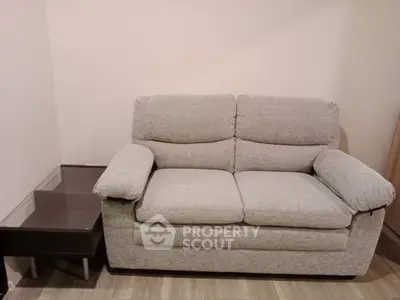 Cozy living room with plush gray sofa and modern side table, perfect for relaxation.