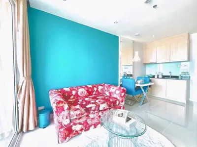 Bright living room with floral sofa and modern kitchen in open layout apartment.