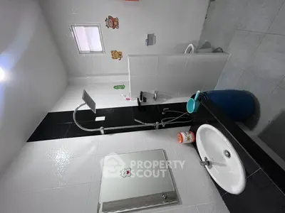 Modern bathroom with sleek black and white tiles, featuring a shower and stylish sink.