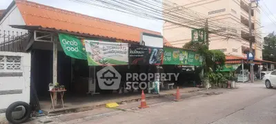 Street view of commercial property with GrabFood banners and outdoor seating area.
