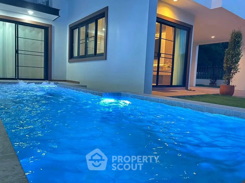 Luxurious modern home with illuminated private pool and elegant exterior lighting.