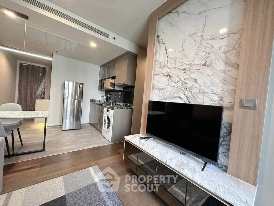 Modern open-plan living room with kitchen, featuring marble accents and sleek appliances.